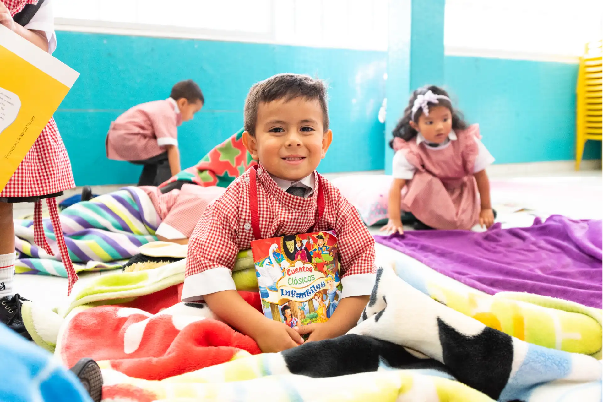 Niño sonriente del Liceo Moderno American School leyendo un libro de cuentos clásicos infantiles